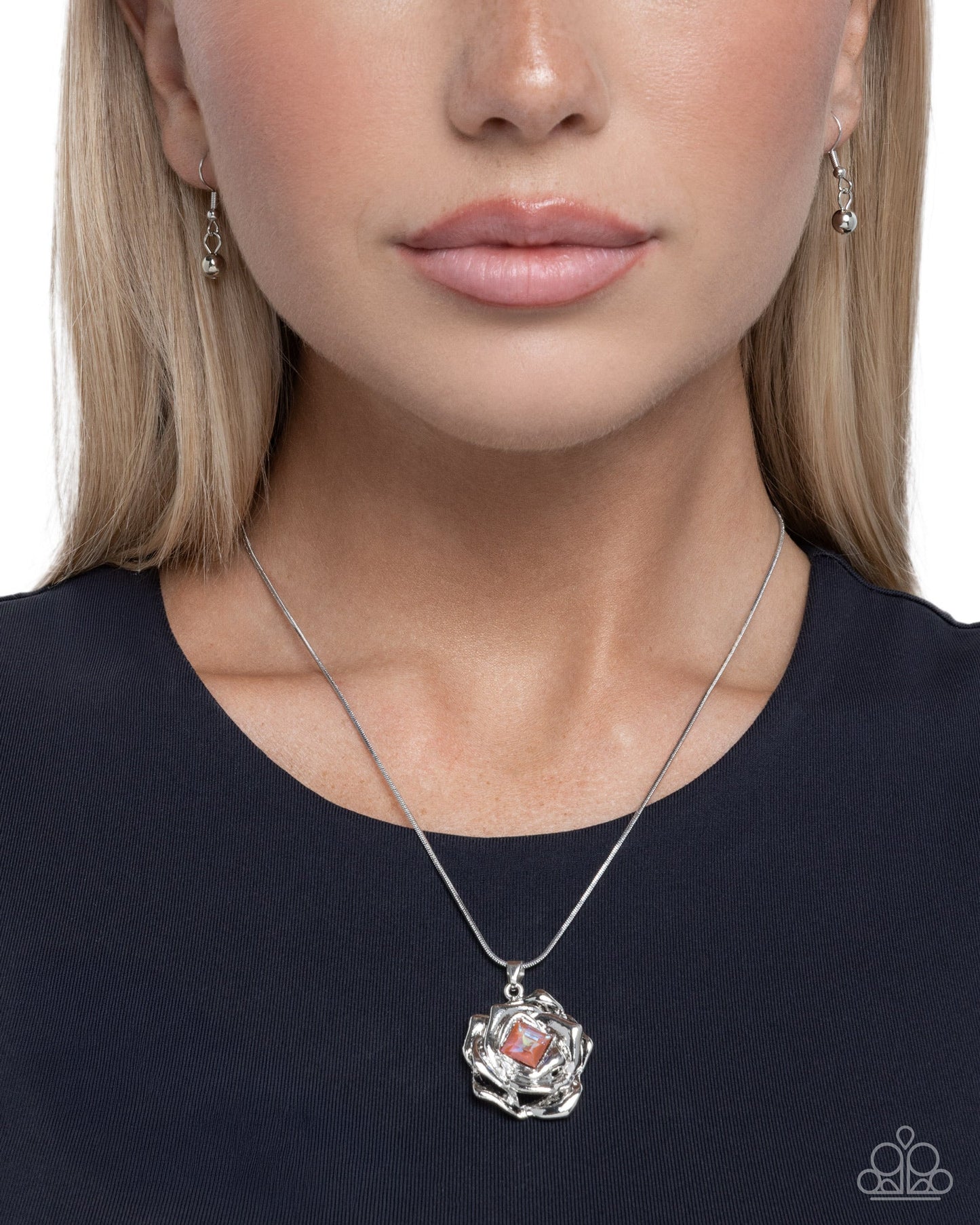 Close-up of a woman wearing a silver necklace with a pendant on a plain background