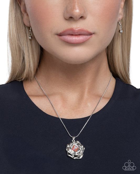 Close-up of a woman wearing a silver necklace with a pendant on a plain background